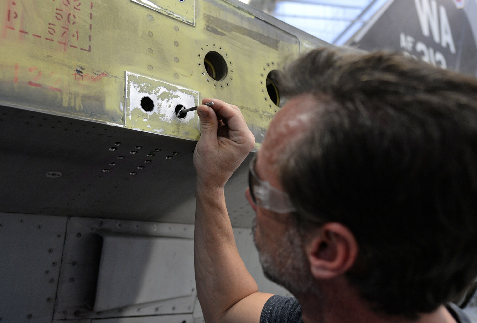 Mr. Ryan Wagstaff, 576 AMXS Machinist, uses a telescoping gauge while inspecting wing-attachment points. These inspections help determine whether the holes meet the required tolerance or new bushings are necessary. (U.S. Air Force Photo by Alex R. Lloyd)