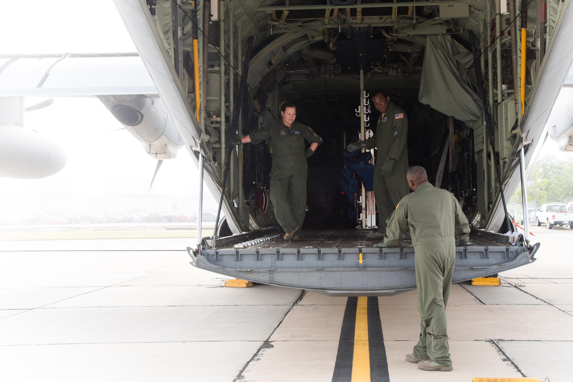 Tech. Sgt. Jenna Daniel, Staff Sgt. Larry Banks and Master Sgt. Troy Bickham, 53rd Weather Reconnaissance Squadron loadmasters, prepare to load equipment onto a WC-130J Super Hercules aircraft on a foggy morning April 12 at Keesler Air Force Base, Mississippi. (U.S. Air Force photo/Staff Sgt. Heather Heiney)