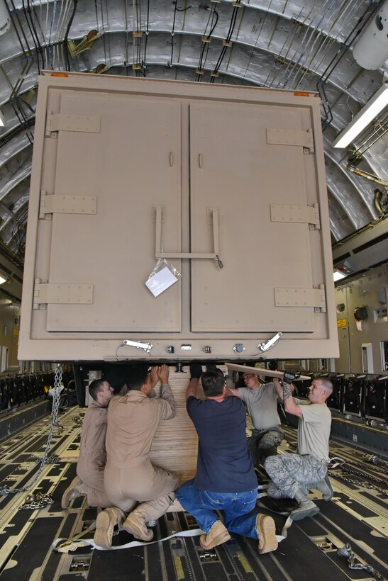 Personnel from Travis and Kirtland Air Force Bases stack pallets under the Universal Ground Nuclear Detonation Detection Terminal trailer on a C-17 Globemaster III at Kirtland Air Force Base, March 21. Wood pallets were added to secure the UGNT’s stability during its flight. (U.S. Air Force photo by Ken Moore)
