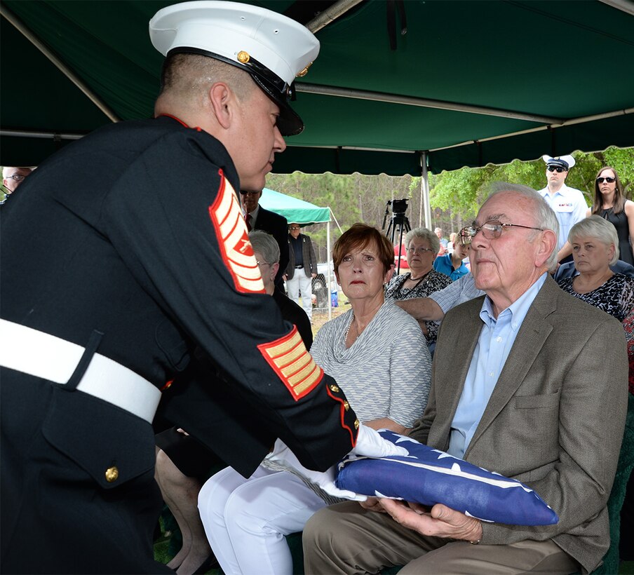 Master Sgt. Robert Nolasco, staff noncommissioned-in-charge, Funeral Detail, Marine Corps Logistics Base Albany, presents an American flag to Larry Odom during the burial of Marine Pfc. James O. Whitehurst at Cowarts Baptist Church Cemetery in Cowarts, Ala., April 12. Whitehurst was killed in action while fighting the Japanese at the battle of Tarawa during World War II, Nov. 20, 1943.