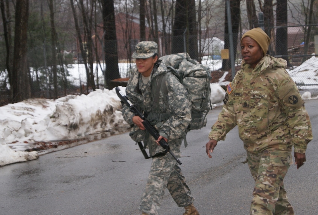 (Right) Command Sgt. Maj. Sharon Campbell motivates competitor Sgt. Nicole Paese as she nears the end of the 6.2-mile ruck march at Fort Devens, Massachusetts, April 4, 2017, as part of the 2017 Joint 80th Training Command and 99th Regional Support Command Best Warrior Competition.