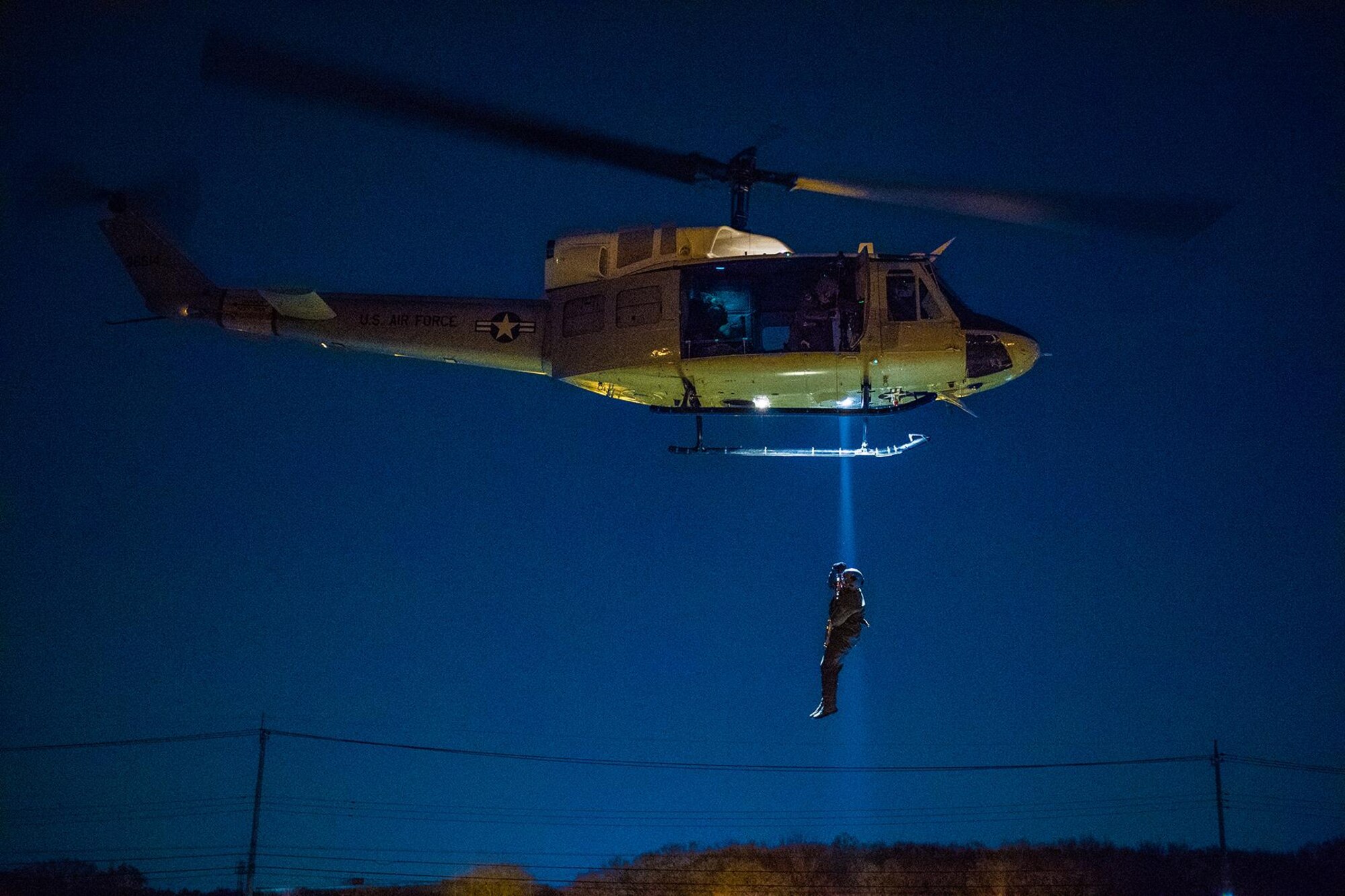 Staff Sgt. Nicholas A. Poe, a 459th Airlift Squadron special missions aviator, looks out the window of a UH-N1 Iroquois, through night vision goggles, during a night hoist training exercise April 4, 2017, in Tokyo. The aircrew trained with night vision goggles to prepare for missions that must be conducted at night. (U.S. Air Force photo/Airman 1st Class Donald Hudson)