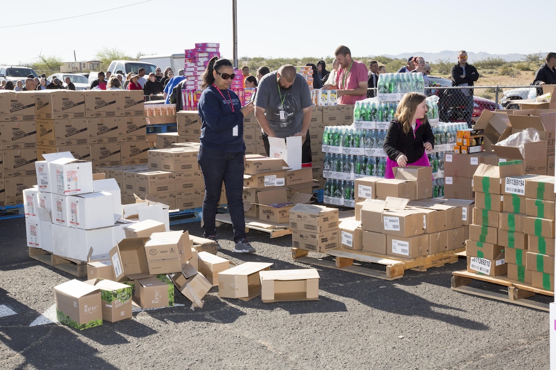 (Left) Sandra Murray takes pictures of the food donated to the charitable groups, Blessings and Military Blessings in the parking lot of Bethany Christian Fellowship Church in Barstow, as volunteers prepare to hand out the foodstuffs to the crowd gathered along the fence, March 24. Murray founded the charities and is the wife of an active duty Army Soldier stationed at Marine Corps Logistics Base Barstow.