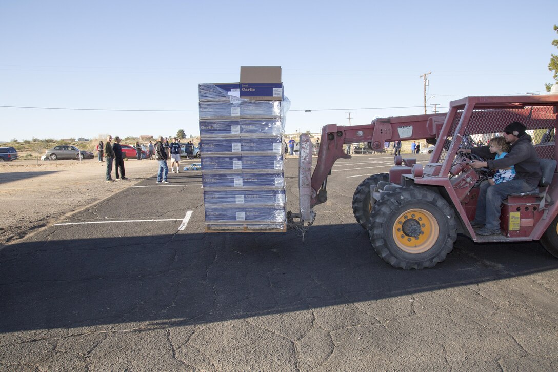 Andrew Hecker and his 2-year-old son Ezekiel unload pallets of food in preparation for stacking in the parking lot of the Bethany Christian Fellowship Church in Barstow, March 24. Hecker donates his time to the food handout organized by the charitable groups Blessings and Military Blessings. The forklift is donated by Silver Valley Propane, Hecker’s employer.