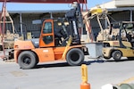 Carrie Eaton, tractor operator, tows a broken forklift to a back shop to be repaired April 4. Eaton and her colleagues at Material Equipment Handling section are responsible for moving all vehicles, parts, and any other materials necessary to complete work on a vehicle at Production Plant Barstow, Marine Depot Maintenance Command aboard the Yermo Annex of Marine Corps Logistics Base Barstow, Calif.