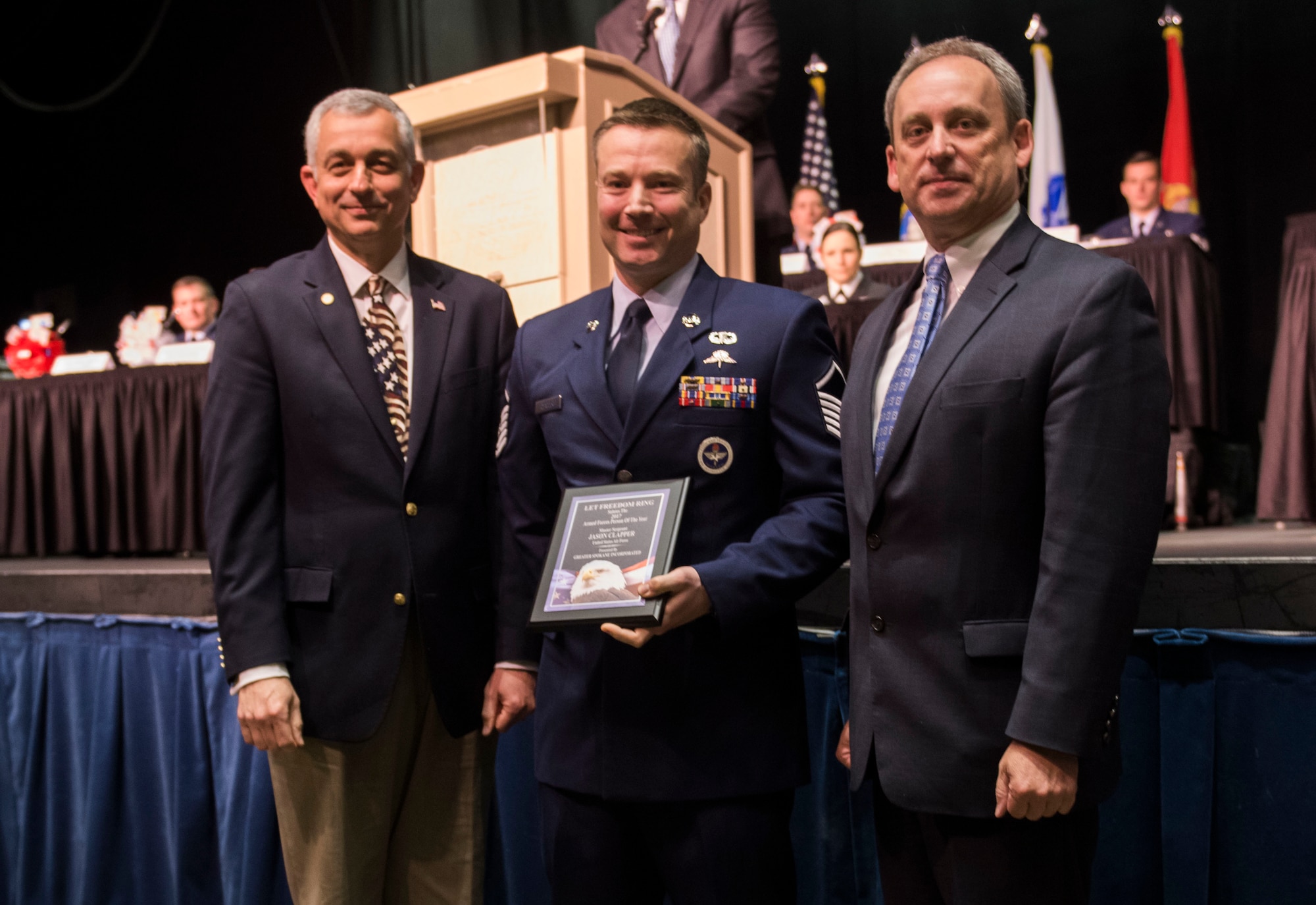 Master Sgt. Jason Clapper, 22nd Training Squadron superintendent, receives the 2017 Armed Forces Persons of the Year award, category Active Duty grades E-7 through E-9, from Todd Mielke, Greater Spokane Incorporated CEO, and retired Brigadier General Roger Watkins, during the 61st annual Let Freedom Ring breakfast Apr. 14, 2017, at Northern Quest Casino in Spokane, Washington. The event honored military members from all branches, and recognized the Armed Forces Persons of the Year. (U.S. Air Force photo/Airman 1st Class Sean Campbell)