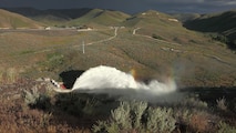 View of the "Rooster Tail", Lucky Peak Dam, May 25, 2008, Boise, Idaho. A popular springtime attraction is the "Rooster Tail" which results from the discharge of water through the original release structures of the dam under pressure from the lake above.  Using a "flip bucket" to direct the spray high into the air, the erosive, scouring force of the water is greatly dissipated as it rises, rests and slowly falls back to the stream channel.
The Rooster Tail only uses water from large releases required for flood risk management that exceed powerhouse capacity, thus no water is wasted for the display.   
It occurred daily until 1986 when construction of the Lucky Peak Power Plant Project started.  
