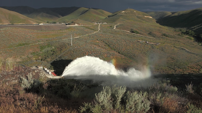 View of the "Rooster Tail", Lucky Peak Dam, May 25, 2008, Boise, Idaho. A popular springtime attraction is the "Rooster Tail" which results from the discharge of water through the original release structures of the dam under pressure from the lake above.  Using a "flip bucket" to direct the spray high into the air, the erosive, scouring force of the water is greatly dissipated as it rises, rests and slowly falls back to the stream channel.
The Rooster Tail only uses water from large releases required for flood risk management that exceed powerhouse capacity, thus no water is wasted for the display.   
It occurred daily until 1986 when construction of the Lucky Peak Power Plant Project started.  
