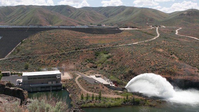 View of the "Rooster Tail", Lucky Peak Dam, May 25, 2008, Boise, Idaho. A popular springtime attraction is the "Rooster Tail" which results from the discharge of water through the original release structures of the dam under pressure from the lake above.  Using a "flip bucket" to direct the spray high into the air, the erosive, scouring force of the water is greatly dissipated as it rises, rests and slowly falls back to the stream channel.
The Rooster Tail only uses water from large releases required for flood risk management that exceed powerhouse capacity, thus no water is wasted for the display.   
It occurred daily until 1986 when construction of the Lucky Peak Power Plant Project started.  
