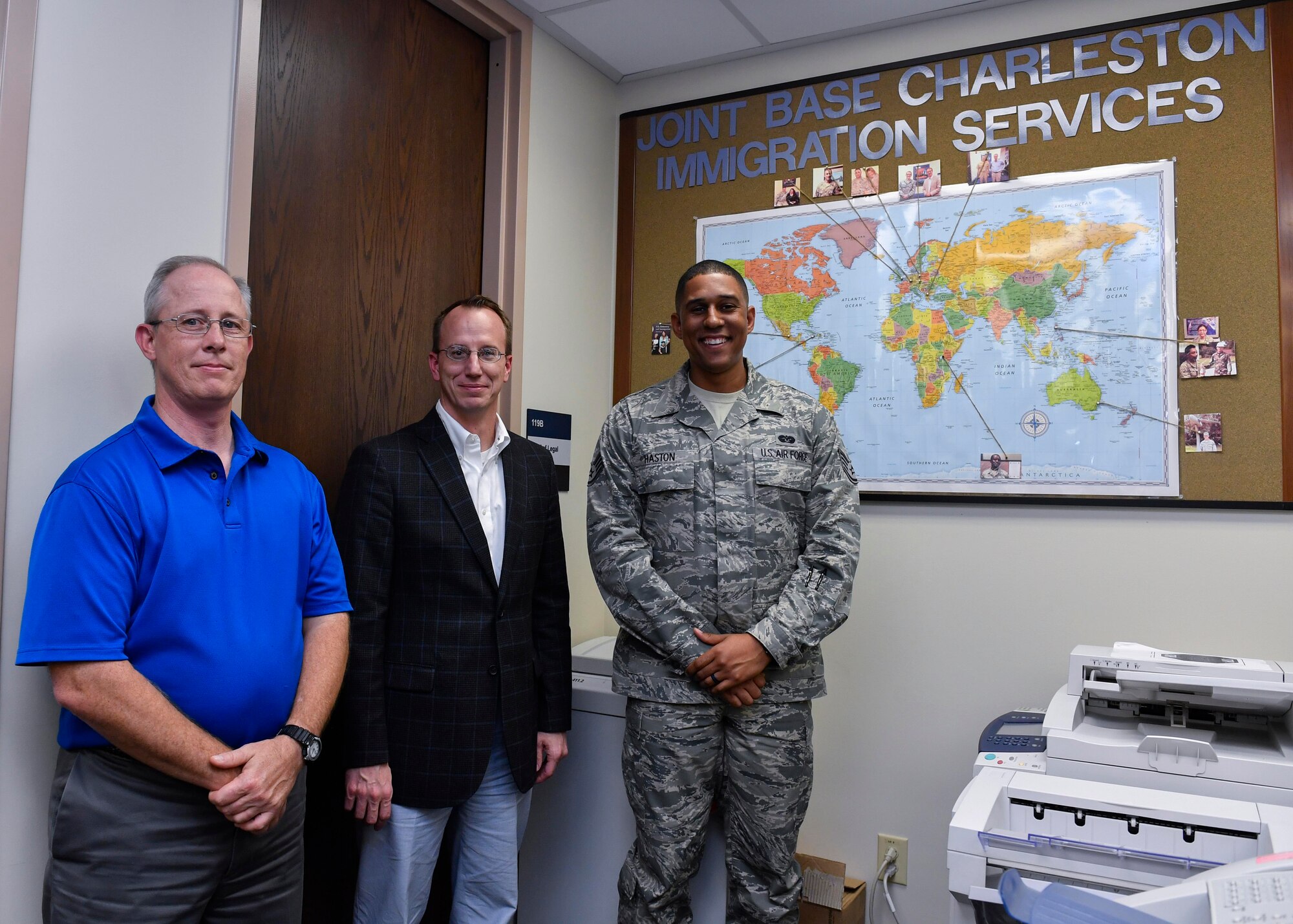 Robert Yancey, left, 628th Air Base Wing Office of the Staff Judge Advocate discharge clerk, Brad Stanley, center, 628th ABW JA Civil Law division chief, and Staff Sgt. William Haston, right, 628th ABW JA NCO in charge of military justice, showcase photos of a few of the people they have helped obtain citizenship here, April 13, 2017. Members of 628th ABW JA have assisted more than 300 service members and their families receive their citizenship since the Joint Base Charleston Immigration Clinic was created in 2008.