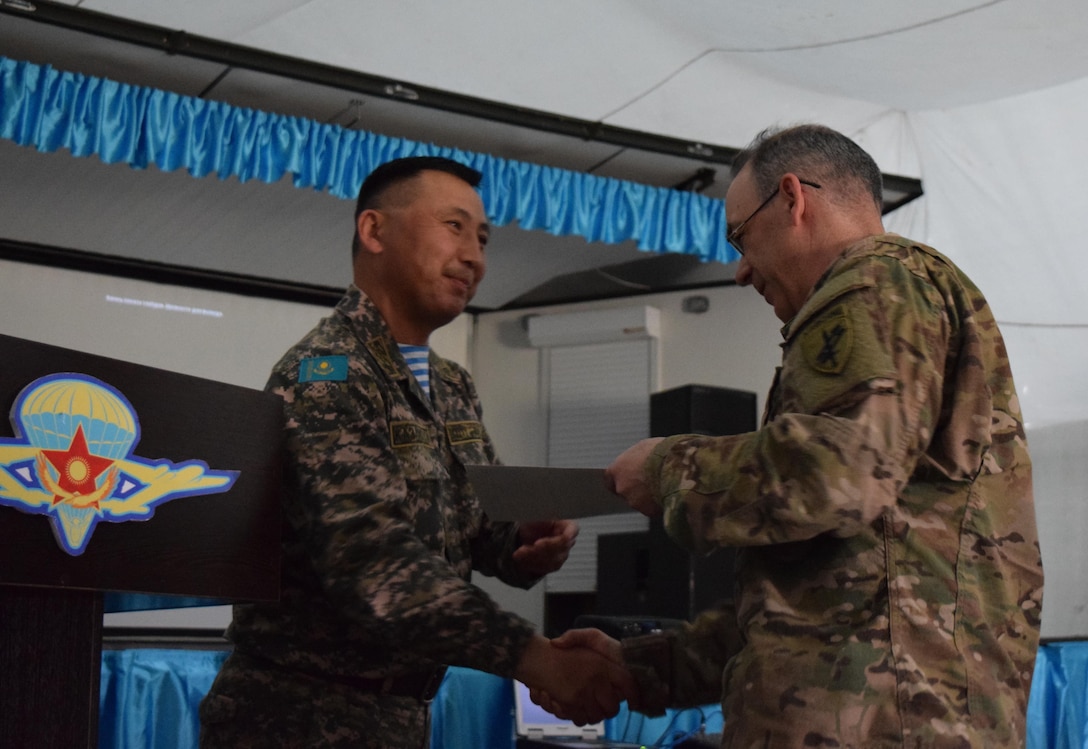 Lt. Col. Bulat Dusembayev, commander of the Kazakhstan Peacekeeping Brigade, left, presents Lt. Col. James Becker, 352nd Civil Affairs Command, with a certificate of appreciation during the closing day of Steppe Eagle Koktem, Apr. 11, 2017, at Illisky Training Center, Kazakhstan.