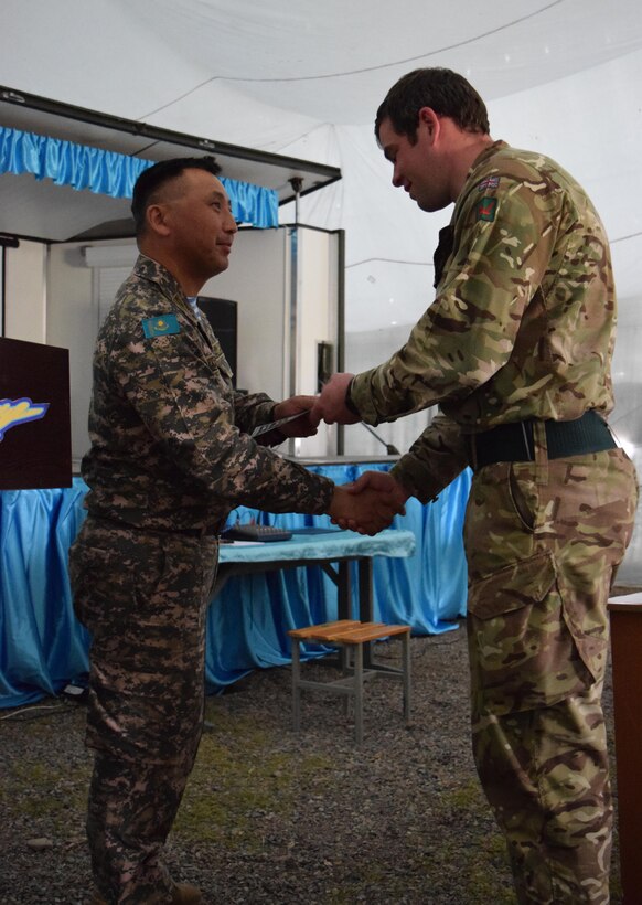 Lt. Col. Bulat Dusembayev, commander of the Kazakhstan Peacekeeping Brigade, left, presents Cpl. Christopher Meek, 1st Battalion, The Rifles, 160 Brigade, with a certificate of appreciation during the closing day of Steppe Eagle Koktem, Apr. 11, 2017, at Illisky Training Center, Kazakhstan.