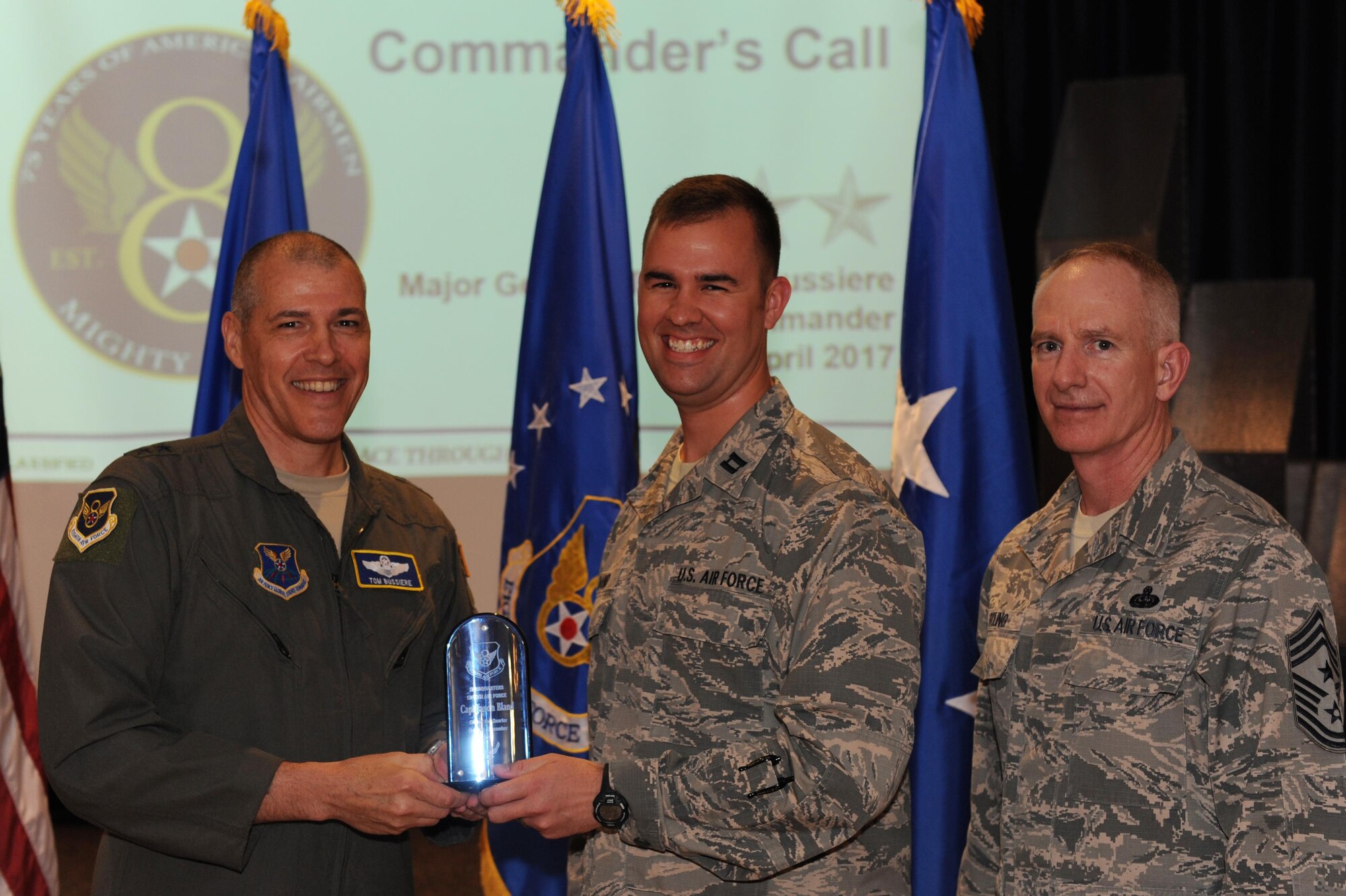 U.S. Air Force Maj. Gen. Thomas Bussiere, Eighth Air Force commander, left, and Chief Master Sgt. Alan Boling, Eighth Air Force command chief, far right, recognizes Capt. Jason Bland, Headquarters Eighth Air Force staff, as a Fourth Quarter Award winner during a Headquarters Eighth Air Force commanders call at Barksdale Air Force Base, La., April 12, 2017. Various topics pertinent to the organization were discussed throughout the event, followed by a question and answer engagement session with the Airmen. (U.S. Air Force photo by Senior Airman Erin Trower)
