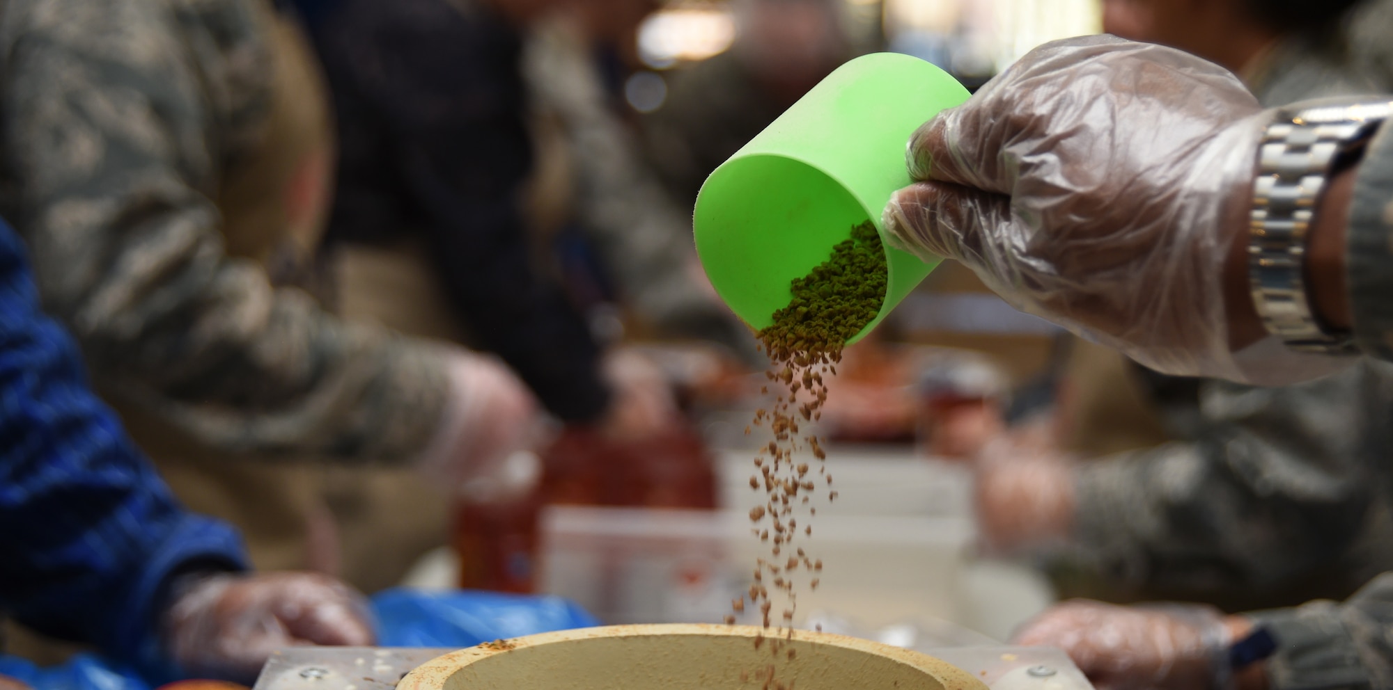 Maj. Kelley Thomspon, 4th Space Control Squadron chief engineer, pours rice into a funnel during the Kids Against Hunger volunteer event at Schriever Air Force Base, Colorado, Tuesday, April 11, 2017. Each meal package consisted of rice, soy, black beans and spices. (Air Force photo/Senior Airman Arielle Vasquez)