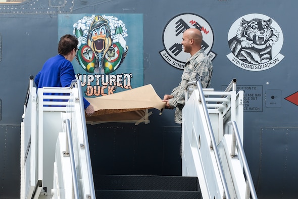 Becky Thatcher, daughter of the late Doolittle Raider Staff Sgt. David Thatcher, and U.S. Air Force Tech. Sgt. William Hatten from 28th Maintenance Squadron from Ellsworth Air Force Base, S.D., Ruptured Duck dedicated crew chief, unveil the newest rendition of the Ruptured Duck artwork during a ceremony for the new Ruptured Duck artwork, Apr. 17, 2017 at Wright-Patterson Air Force Base, Ohio. The original artwork featured a cross-eyed duck, wearing a leather helmet, staring out over crossed crutches. (U.S. Air Force photo by Wesley Farnsworth)