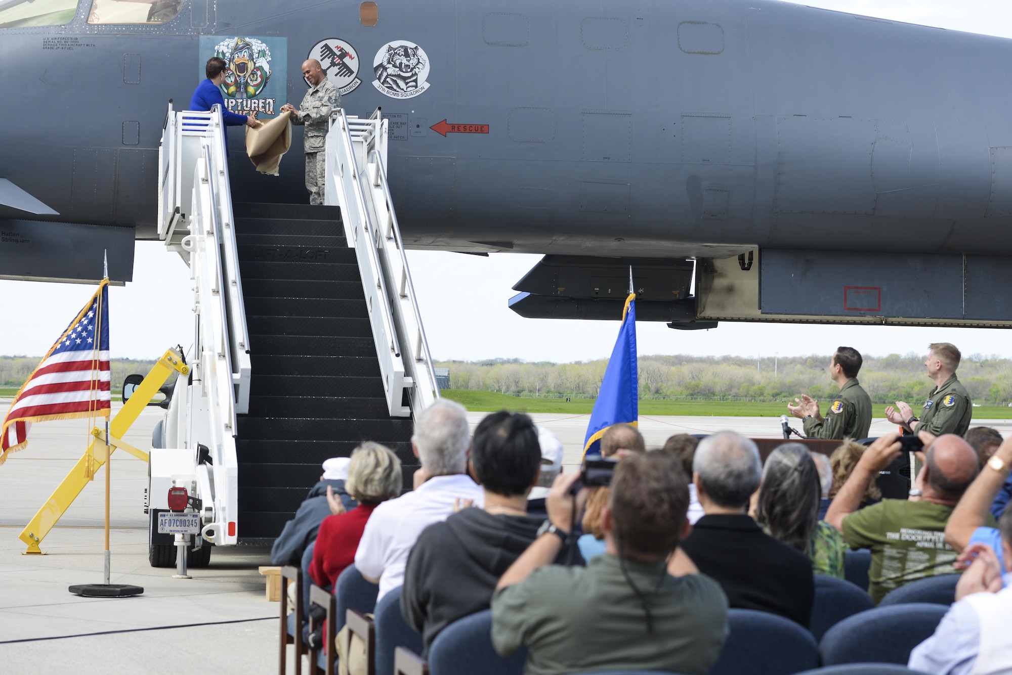 Becky Thatcher, daughter of the late Doolittle Raider Staff Sgt. David Thatcher, and U.S. Air Force Tech. Sgt. William Hatten, 28th Maintenance Squadron from Ellsworth Air Force Base, S.D., Ruptured Duck dedicated crew chief, unveil the newest rendition of the Ruptured Duck artwork in front of a crowd during a ceremony, Apr. 17, 2017 at Wright-Patterson Air Force Base, Ohio. The original artwork featured cross-eyed duck, wearing a leather helmet, staring out over crossed crutches. (U.S. Air Force photo by Wesley Farnsworth)