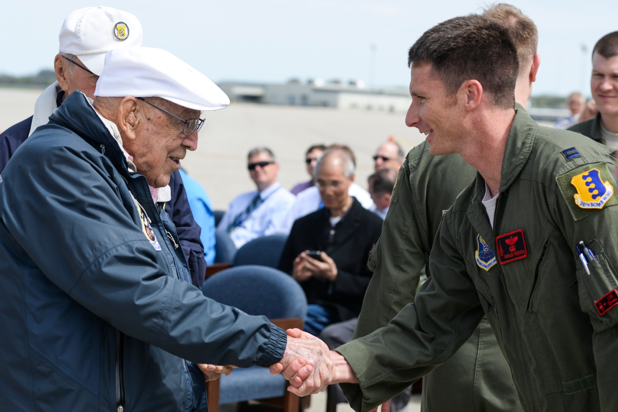 Retired Doolittle Raider, Lt. Col. Dick Cole, presents U.S. Air Force Capt. Michael Riddick, 34th Bomb Squadron B-1 pilot, with a coin at the conclusion of an unveiling ceremony for the new Ruptured Duck artwork, Apr. 17, 2017 at Wright-Patterson Air Force Base, Ohio.  The 34th Bomb Squadron lineage can be traced to one of the original Doolittle Raider squadrons. (U.S. Air Force photo by Wesley Farnsworth)
