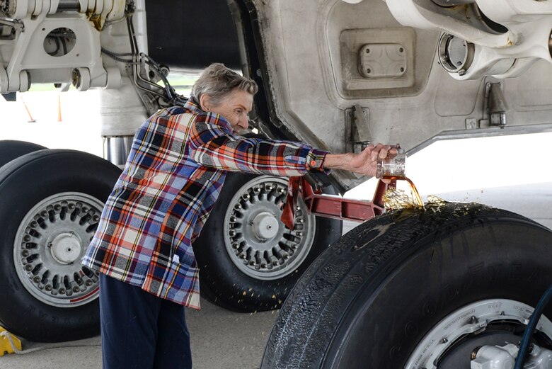 Dawn Thatcher, wife of the late Doolittle Raider Staff Sgt. David Thatcher, pours three fingers of Hennessey on the landing gears of the Ruptured Duck B-1 Aircraft, as part of a ceremony for the new Ruptured Duck artwork, Apr. 17, 2017 at Wright-Patterson Air Force Base, Ohio. The pouring of the most elite of fluids is a long held superstition, which is said to provide a safe flight for those that serve on the aircraft. (U.S. Air Force photo by Wesley Farnsworth)