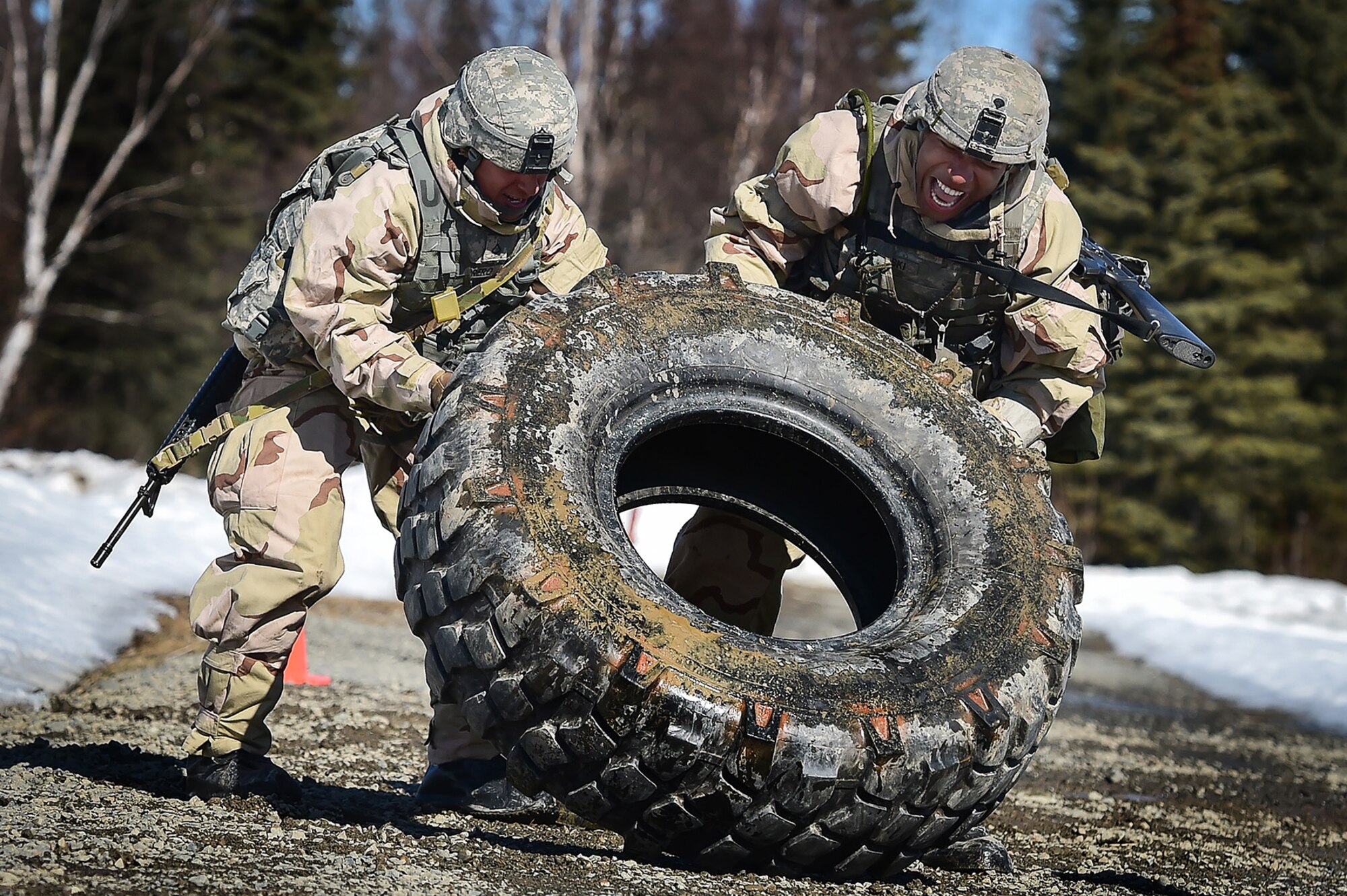 Army Pfc. Esteban Guerrero, a native of Modesto, Calif., left, and Spc. Diego Adamski, a native of Shelton, Wash., both assigned to the 95th Chemical Company, “Arctic Dragons”, 17th Combat Sustainment Support Battalion, U.S. Army Alaska, flip a tire to elevate their heart rates before executing a Joint Service Lightweight Integrated Suit Technology stress fire at McGee range on Joint Base Elmendorf-Richardson, Alaska, April 13, 2017. The JSLIST is the product of a four-Service effort to field a common chemical protective clothing ensemble including a lightweight protective garment, multi-purpose overboots and gloves. 