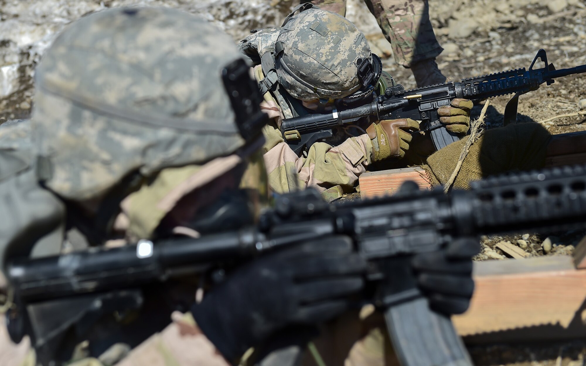 Spc. Michael Forlife, a native of Brooklyn, assigned to the 95th Chemical Company, “Arctic Dragons”, 17th Combat Sustainment Support Battalion, U.S. Army Alaska,  fires his M4 carbine at a target as Spc. Katie McCarthy, a native of Punta Gorda, Fla., taps the forward assist on her carbine while reloading during a Joint Service Lightweight Integrated Suit Technology stress fire at McGee range on Joint Base Elmendorf-Richardson, Alaska, April 13, 2017. The JSLIST is the product of a four-Service effort to field a common chemical protective clothing ensemble including a lightweight protective garment, multi-purpose overboots and gloves. 