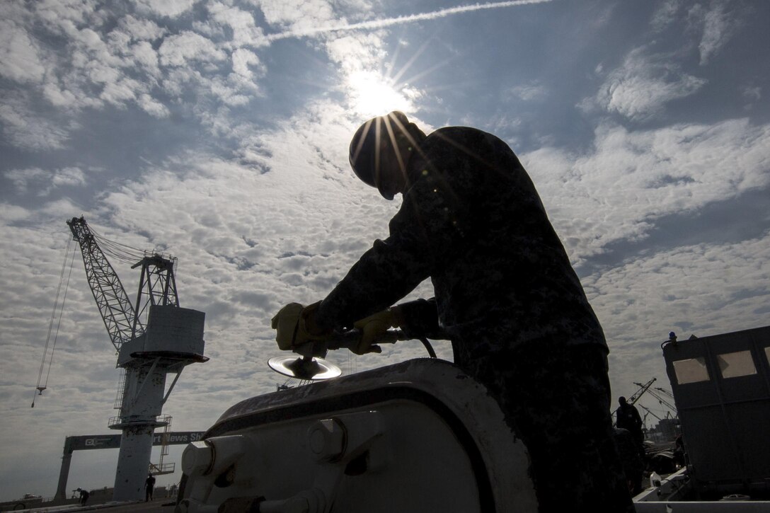 Navy Seaman Trevor Prosser sands a door for repainting on the flight deck of the aircraft carrier USS Abraham Lincoln in Newport News, Va., April 13, 2017. The Lincoln is in the final stages of a four-year overhaul and will be delivered back to the fleet in 2017. Navy photo by Perry Officer 3rd Class Aaron T. Kiser