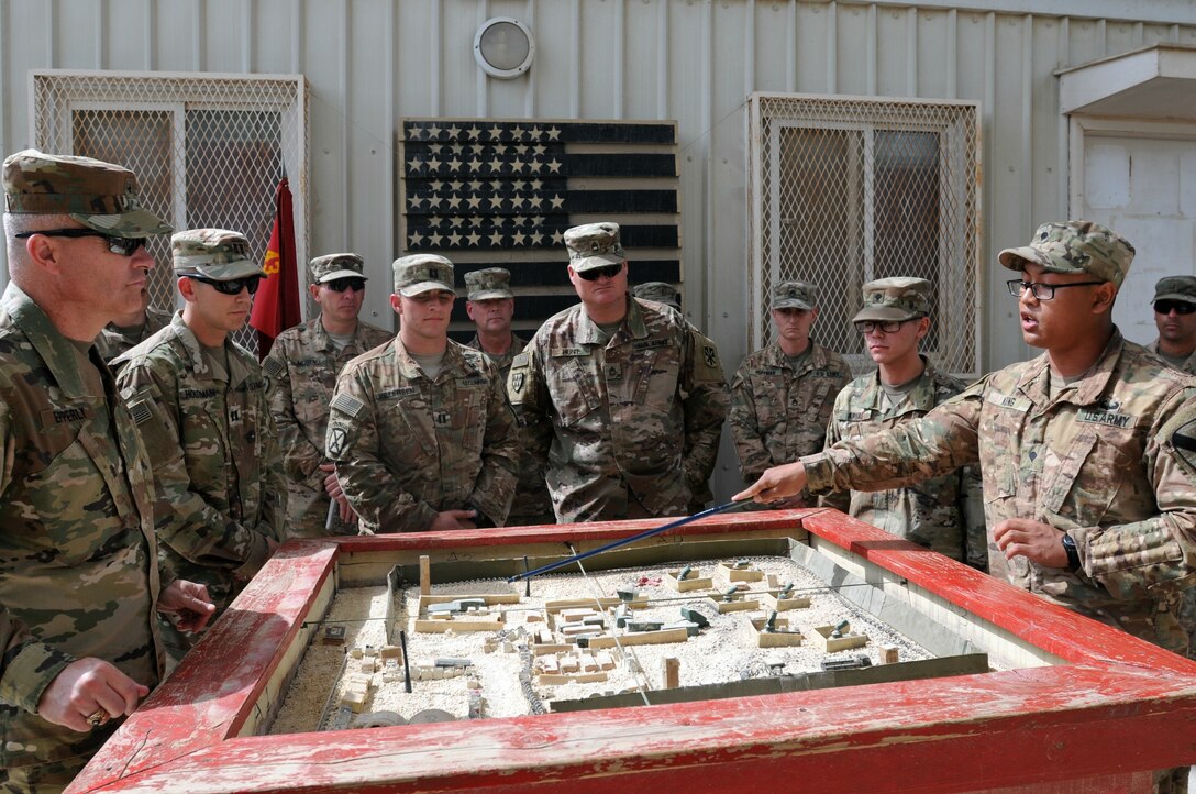Spc. Billy Kong, radio telephone operator for Charlie Company, 1st Battalion, 12th Cavalry Regiment, briefs Brig. Gen. John Epperly, Deputy Commanding General for the 29th Infantry Division, on the layout and function of his battery’s Patriot site March 26, 2017 in Bahrain. Kong was awarded a coin from Epperly for his presentation. Military coins are traditionally given by senior leaders in recognition for performance and excellence.  (U.S. Army photo by Sgt. Kelly Gary, 29th Infantry Division Public Affairs)