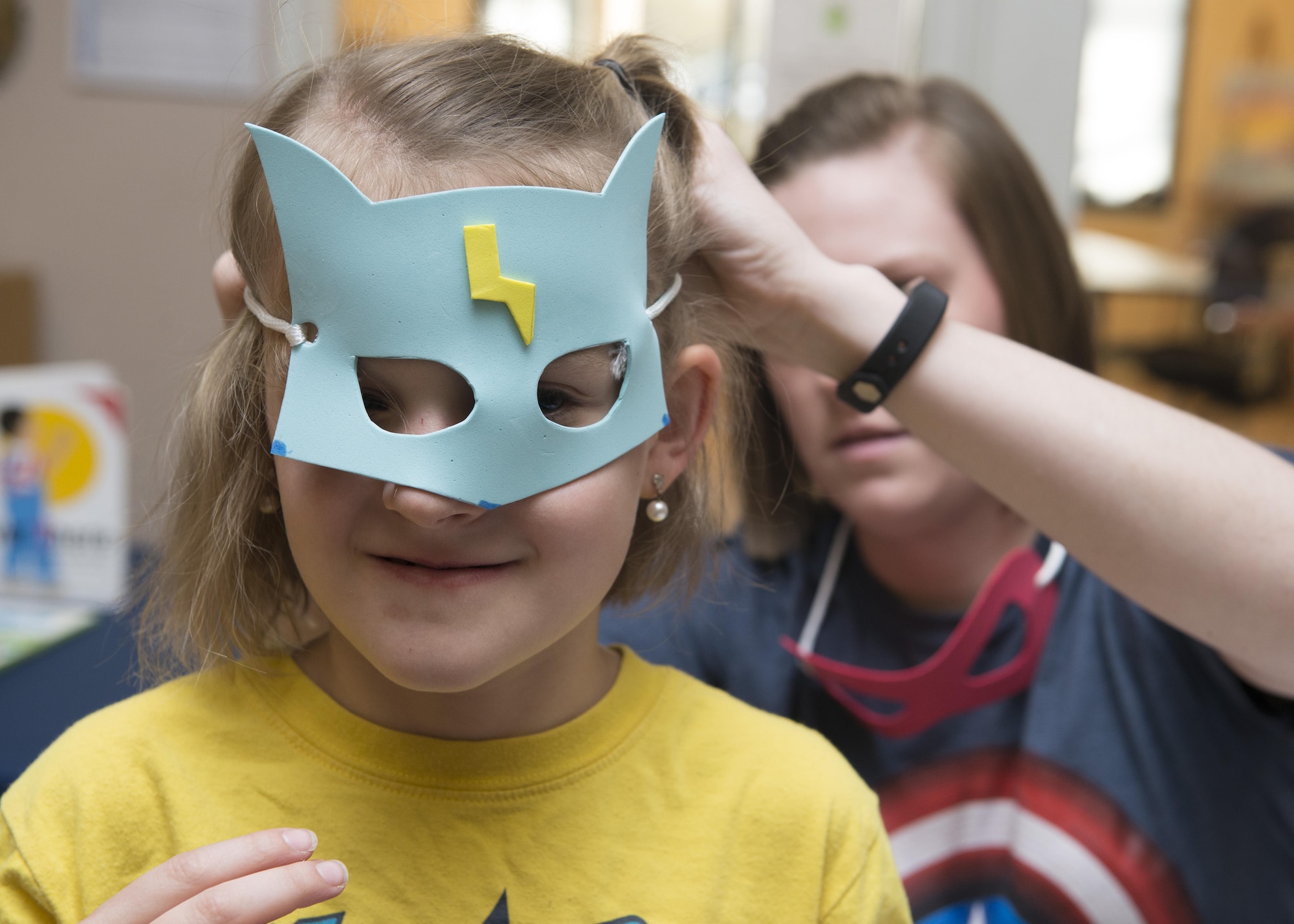 Airman 1st Class Morgan Stanfield, 436th Medical Support Squadron outpatient records, ties a superhero facemask onto Desiree Odom, daughter of Staff Sgt. Zachary Odom, 3d Airlift Squadron loadmaster, at a Deployed Families Dinner April 13, 2017, at the Youth Center on Dover Air Force Base, Del. The dinner is open to all deployed Team Dover Airmen’s family members. (U.S. Air Force photo by Senior Airman Zachary Cacicia)