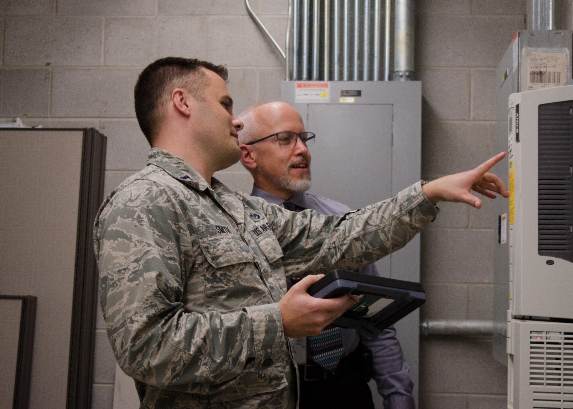 From left, Capt. Tanner Smith, AFCEC's Operations Maintenance Division branch chief, and Bryan Muller, operations management SME, analyze maintenance data on a mobile data device.  The operations directorate is testing the device and hoping to field it with CE operations flights in the near future. Tanner was recently selected as Air Force Installation and Mission Support Center and Air Force Materiel Command Company Grade Officer of the Year.