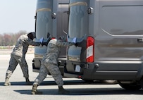 Airman 1st Class Emmanuel Yeboah and Senior Airman Cody Kendall, both assigned to the Air Force Mortuary Affairs Operations, simultaneously close the doors of the mortuary transfer vehicles during Folded Flag 2017 April 11, 2017, on Dover Air Force Base, Del. U.S. Army and Marine Corps carry teams and AFMAO personnel participated in the joint service training exercise that tested the ability of AFMAO to respond to a mass casualty incident. (U.S. Air Force photo by Roland Balik)