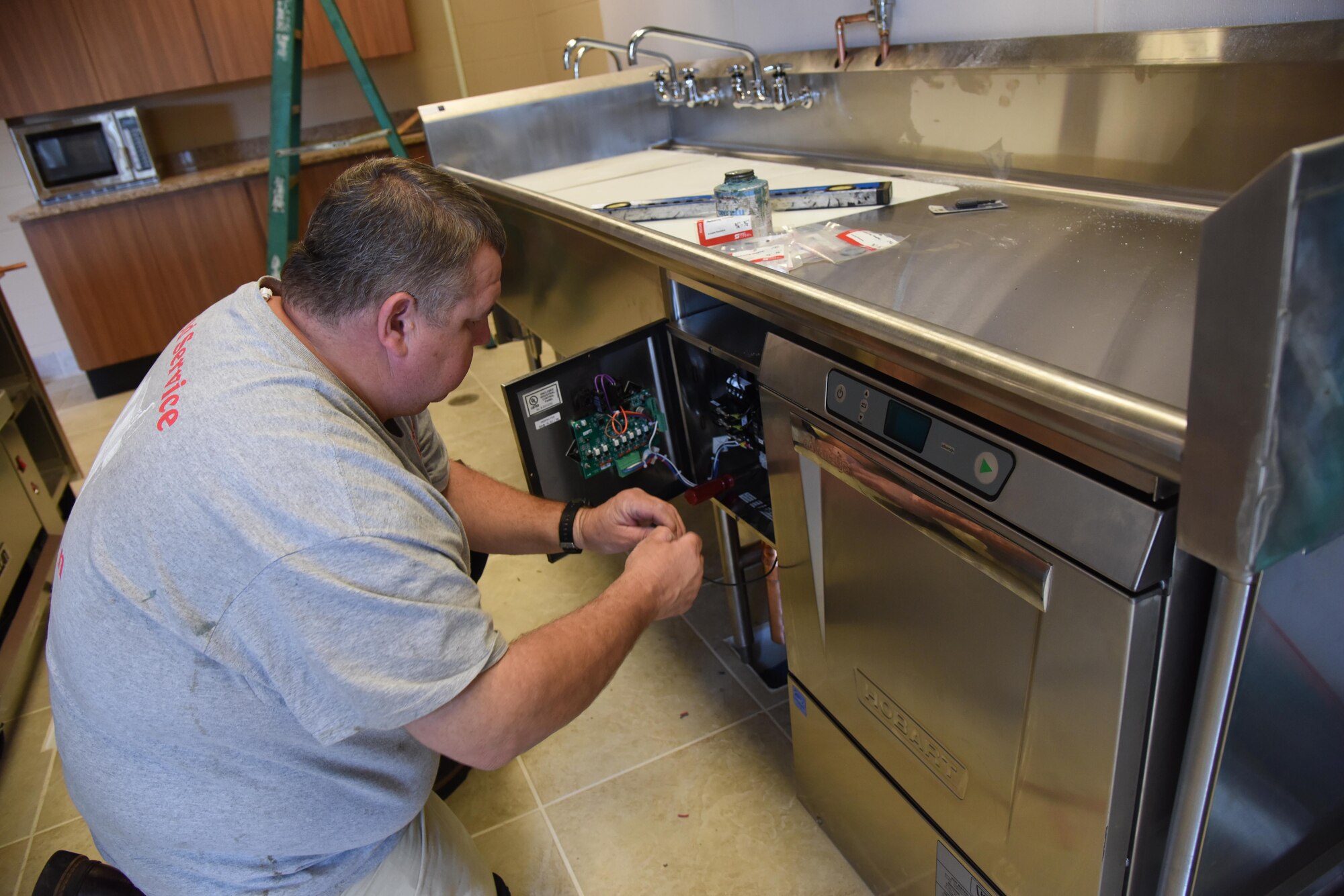 Bo Langford, R and R Food Service installer, connects the solenoid for the garbage disposal at McBride Commons April 11, 2017, on Keesler Air Force Base, Miss. The McBride Commons renovation project will transition the former base library into a common area for those with base access, which includes a children’s library, computer stations, engraving, framing, marketing and print shops and a full kitchen. The planned completion date for the nine-month project is May 2017. (U.S. Air Force photo by Kemberly Groue)