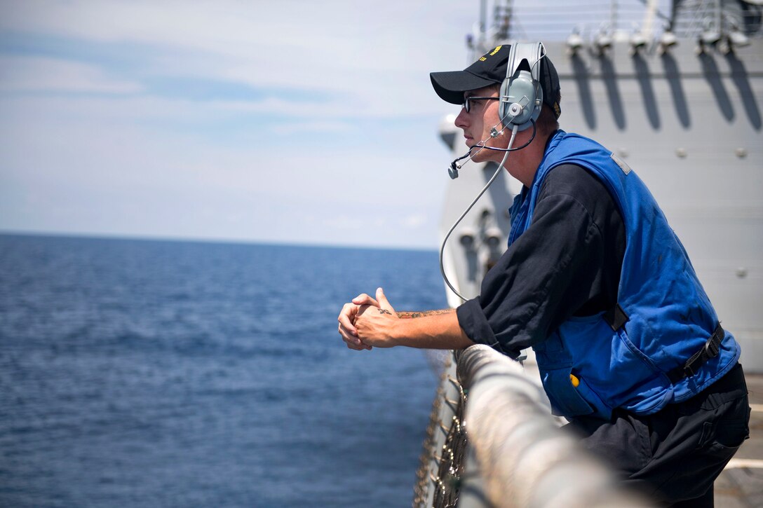 Navy Petty Officer 3rd Class Kieran Robertson peers outward during lookout watch on the flight deck of destroyer USS Michael Murphy in the South China Sea, April 12, 2017. Robertson is a boatswains mate. Navy photo by Petty Officer 3rd Class Danny Kelley