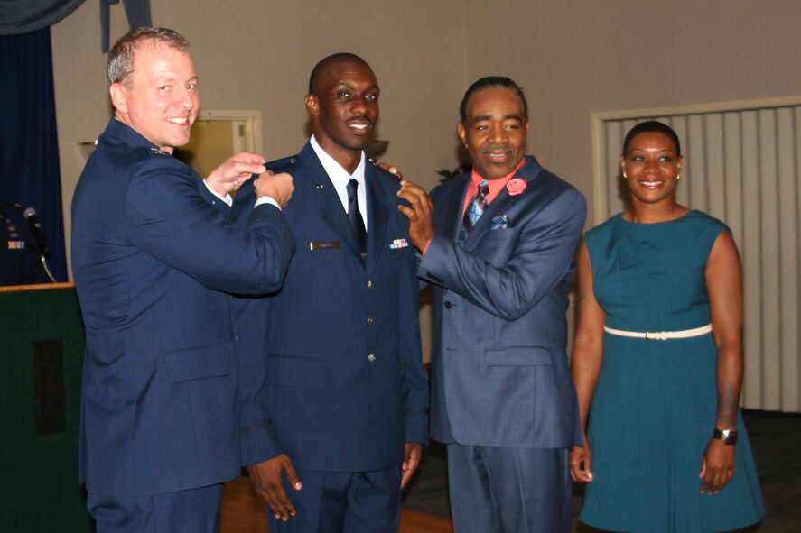 Second Lt. D’Anthony Harris, 413th Aeromedical Staging Squadron medical readiness officer, receives his rank insignia from Col. John Gillespie, former 413th ASTS commander, Pastor Carlton Stephens, and his sister, Khammica Robinson, during a ceremony last year. (Courtesy photo)