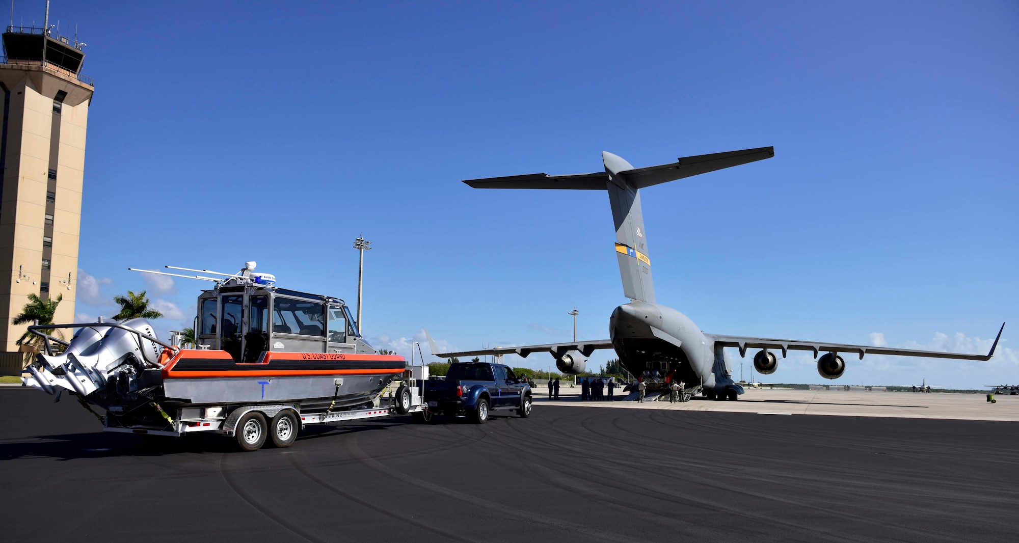 Members of Coast Guard Maritime Safety and Security Team Miami prepare load a small boat onto an Air Force C-17 in Homestead, Florida, on Mar. 8, 2017. An Air Force C-17 airplane transported two MSST boats from Homestead to Tampa to highlight the value of using joint service airlift operations to transport assets over large distances as part of exercise Patriot Sands.