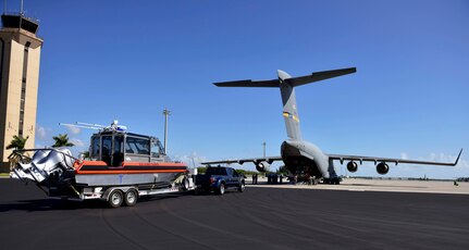 Members of Coast Guard Maritime Safety and Security Team Miami prepare load a small boat onto an Air Force C-17 in Homestead, Florida, on Mar. 8, 2017. An Air Force C-17 airplane transported two MSST boats from Homestead to Tampa to highlight the value of using joint service airlift operations to transport assets over large distances as part of exercise Patriot Sands.