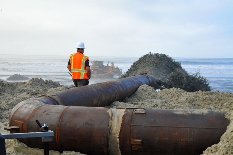 Manson Construction Company pumps material from the Oceanside Harbor entrance channel onto the beach just south of the San Luis Rey River. As the beach widens and provides the route for additional pumping, construction workers will add more sections to the pipe to eventually reach the Oceanside Pier.