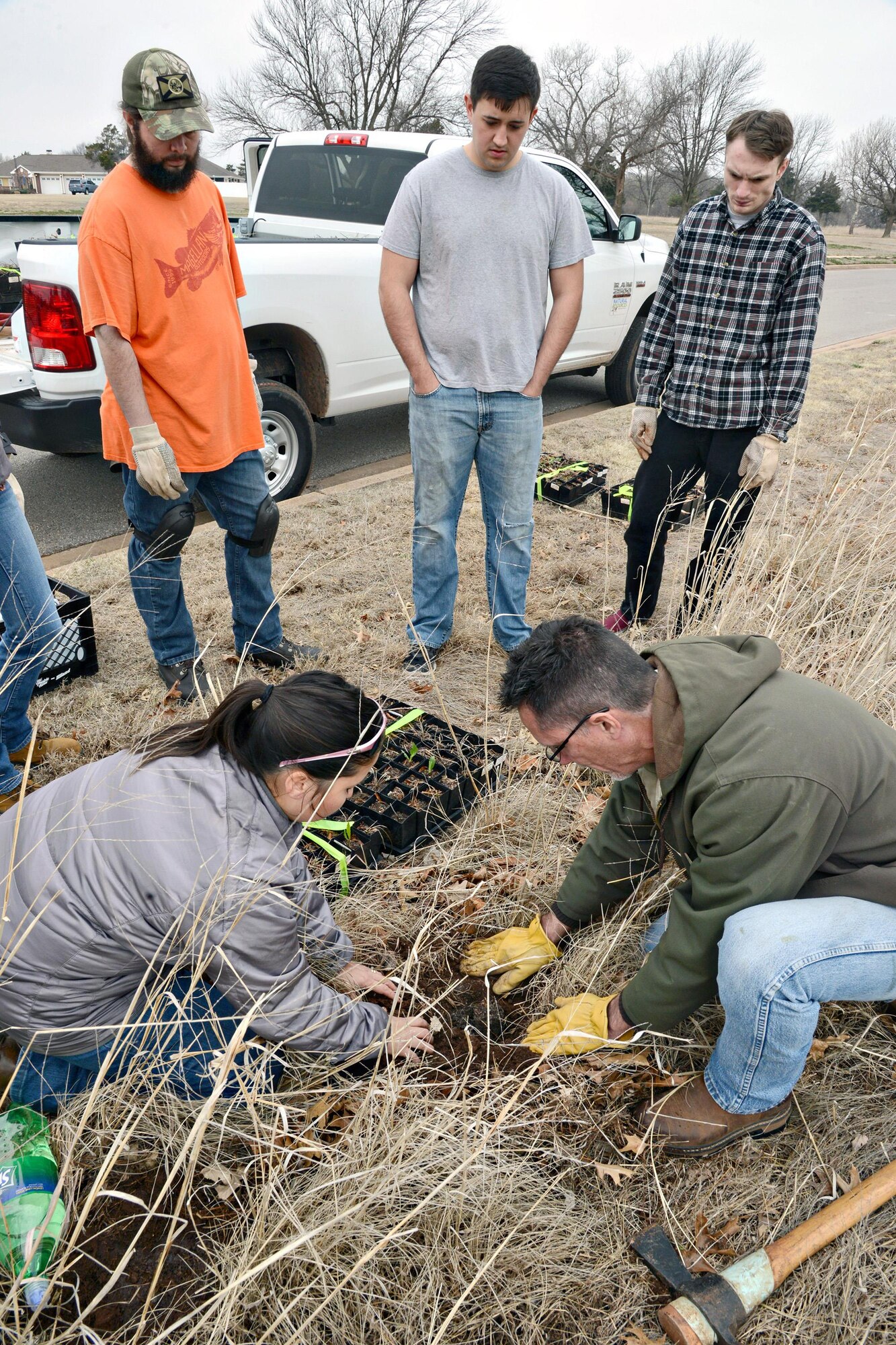 Carlos Carrillo, military spouse, and Senior Airmen Boone Epperson and Tyler Hawke, both with the 72nd Force Support Squadron, from left, watch Donna Nolan, natural resources technician, and John Krupovage, natural resources manager, both with the 72nd Civil Engineering Directorate, as they demonstrate how to correctly plant native wildflowers around the Crutcho Creek area west of the Tinker Club. The flowers are expected to fully develop within the next two to three years. (Air Force photo by Kelly White)