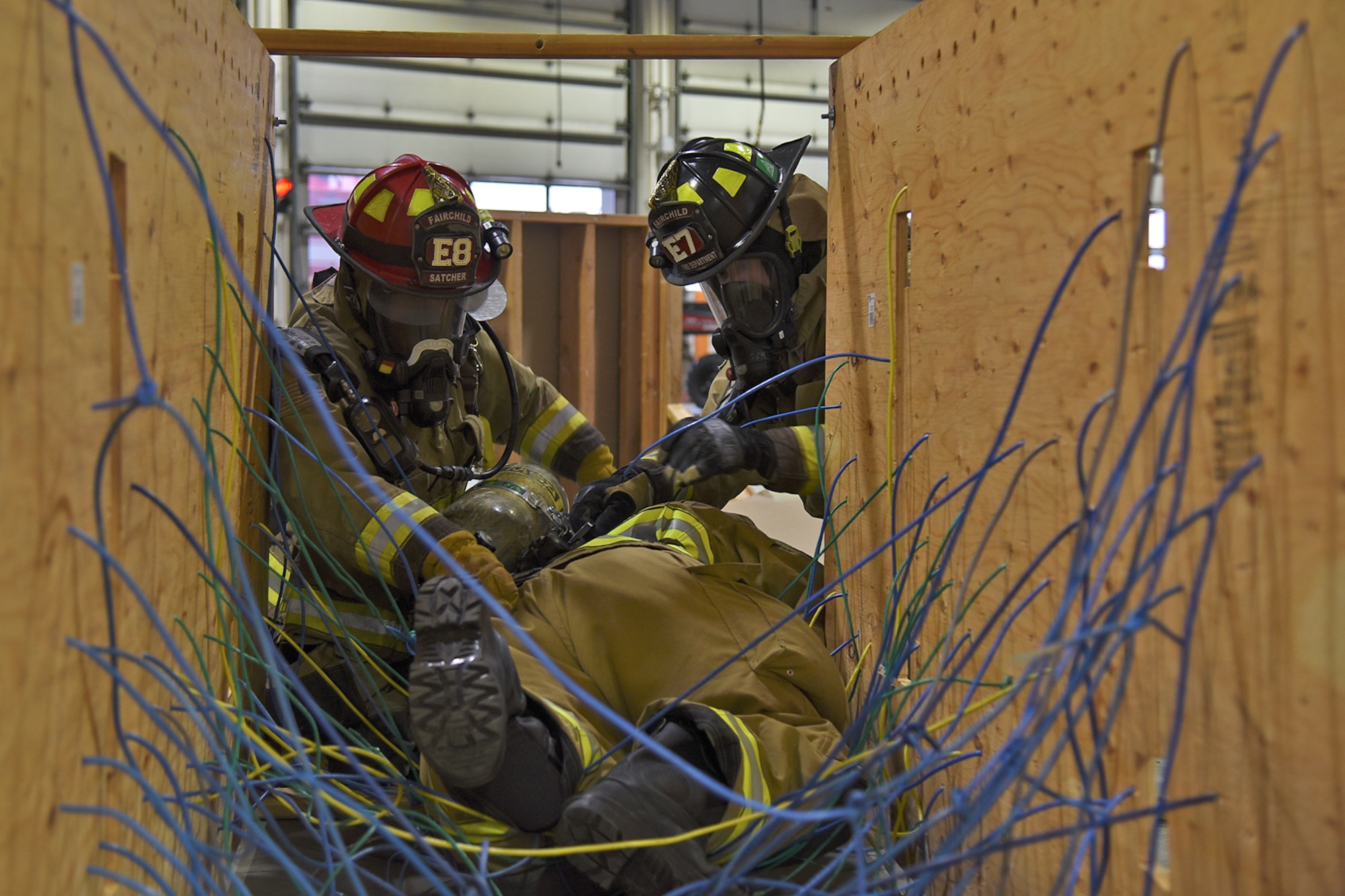 92nd Civil Engineer Squadron firefighters help a fellow firefighter escape the entanglement trainer Mar. 29, 2017, at Fairchild Air Force Base, Washington. The entanglement trainer is one of the various obstacles used during the Rapid Intervention Crew training to simulate a structure fire. (U.S. Air Force photo/Senior Airman Mackenzie Richardson)