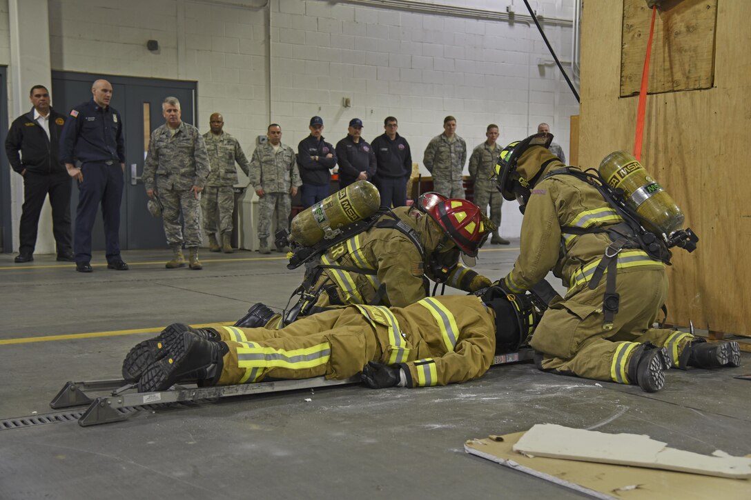 92nd Civil Engineer Squadron firefighters work together to rescue a downed firefighter during a demonstration of their Rapid Intervention Crew training Mar. 29, 2017, at Fairchild Air Force Base, Washington. The demonstration was part of a visit by Col. James Kossler, Air Force Installation and Mission Support Center Detachment 9 commander, to show the progression and implementation of RIC training. (U.S. Air Force photo/Senior Airman Mackenzie Richardson)