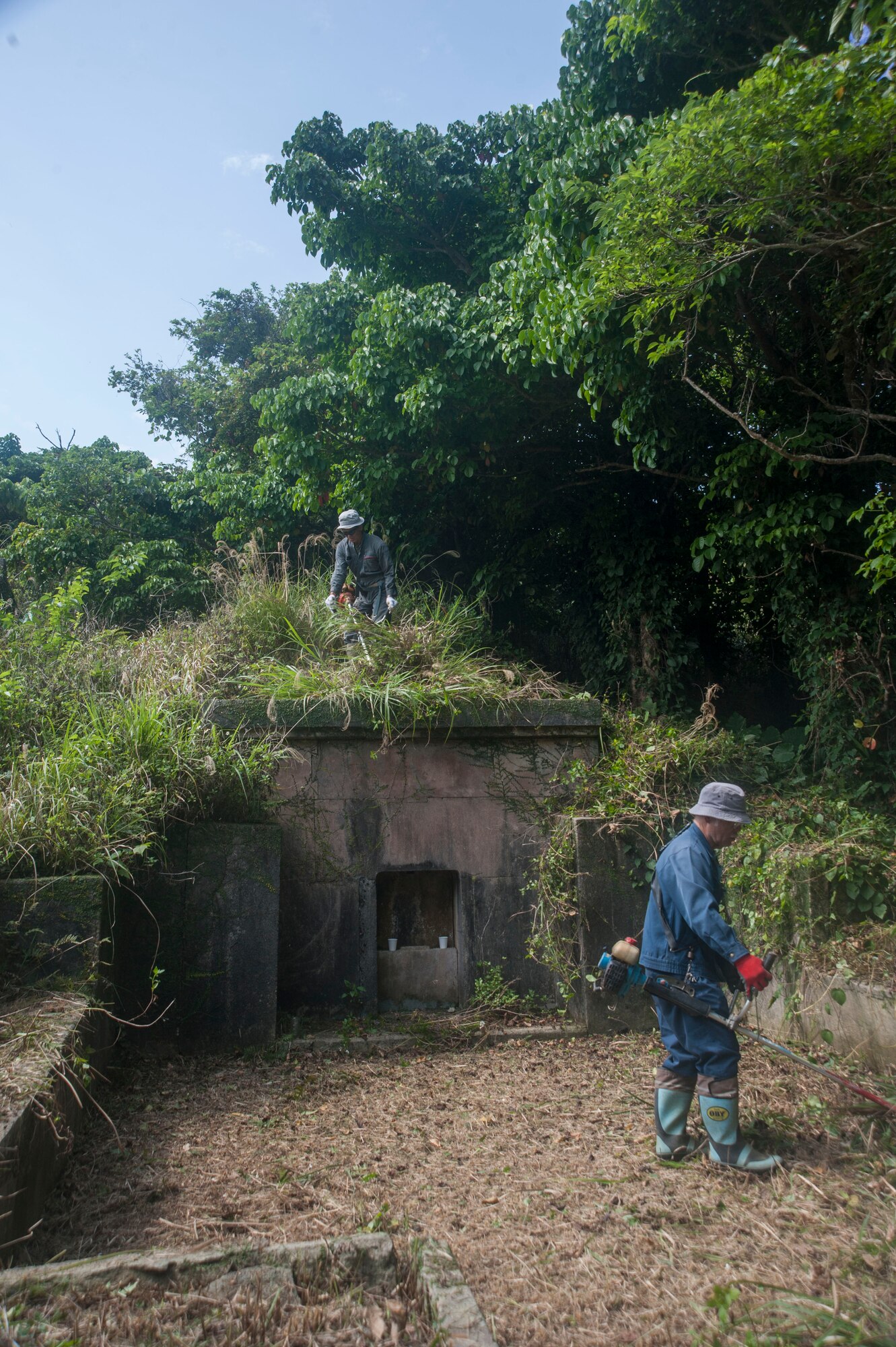 Local Okinawan men remove overgrown vegetation from a family tomb April 9, 2017, at Kadena Air Base, Japan. Members of the communities across the island of Okinawa visit the tombs of their ancestors during the month of April. Airmen from the 18th Munitions Squadron serve as escorts for the families whose ancestral tombs are within the defined area of Kadena. (U.S. Air Force photo by Airman 1st Class Quay Drawdy)