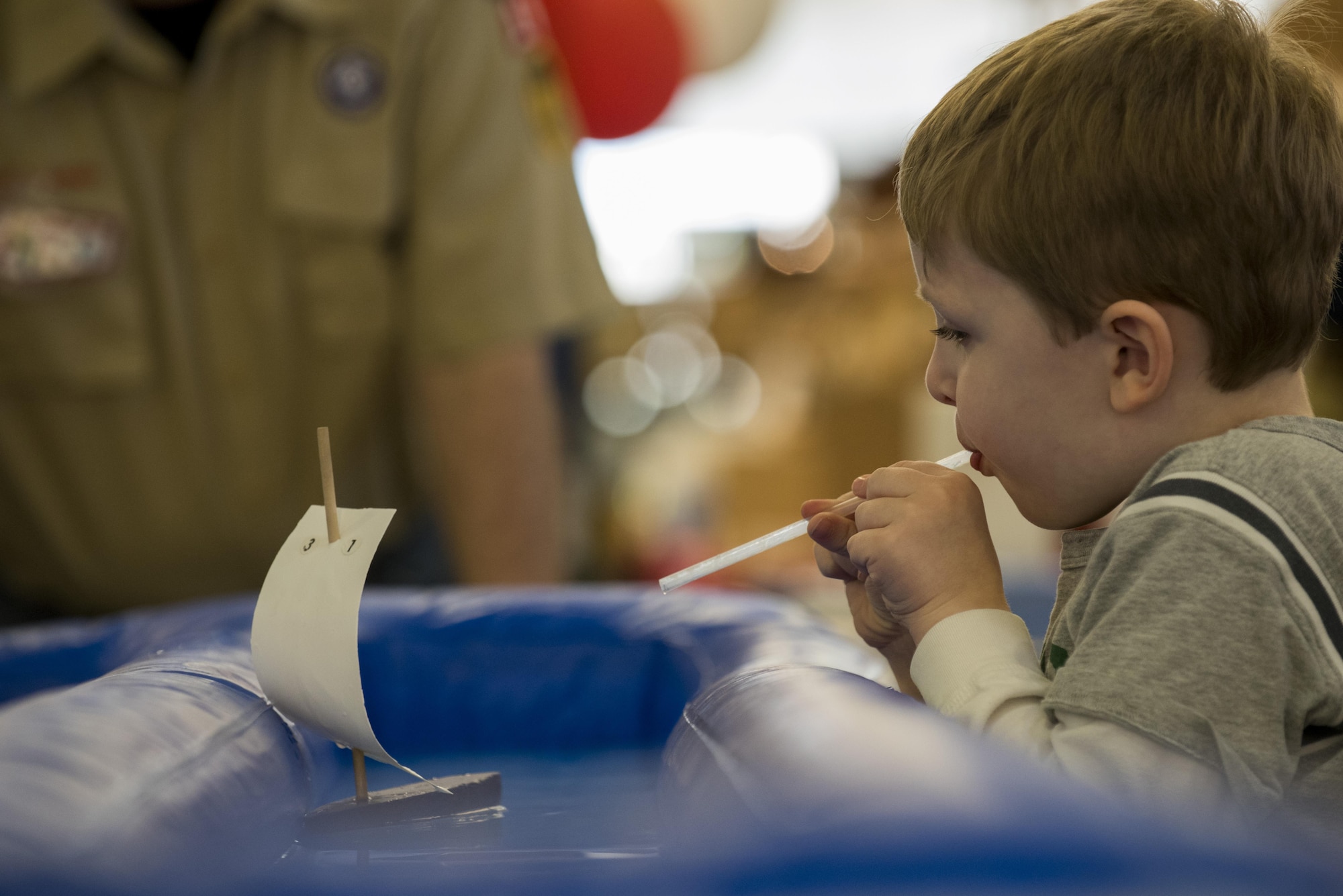 A Spangdahlem child uses a straw to propel a toy boat during the fourth annual Spring Fling event in the Base Exchange at Spangdahlem Air Base, Germany, April 14, 2017. The event was held to bring awareness to the Exceptional Family Member Program and included various activities for children such as face painting, craft making, a bouncing castle and boat races. (U.S. Air Force photo by Airman 1st Class Preston Cherry)