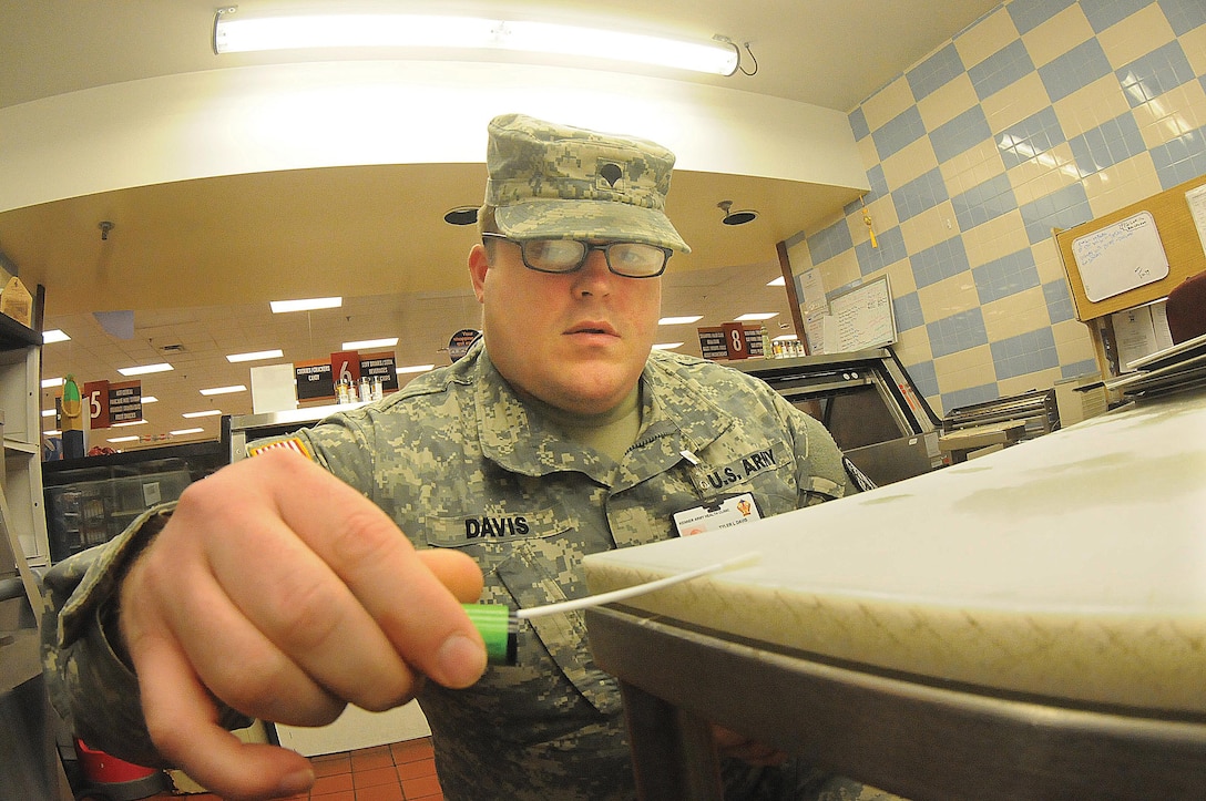 Army Spc. Tyler Davis, a food inspection specialist at Fort Lee, Virginia, uses a swab to test a food preparation area for bacteria at the Defense Commissary Agency store.