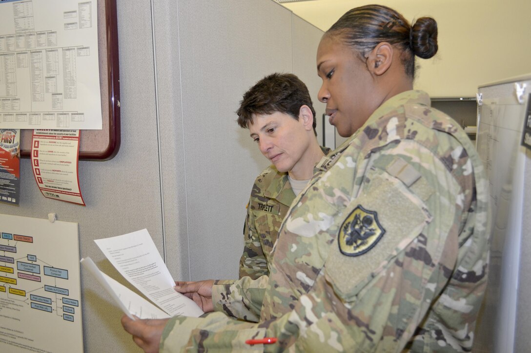 Army Maj. Kellie TRriplett, a veterinary liaison officer, and Army chief Warrant Officer 3 Jemme Neal, consumer safety officer, review an ALFOODACT message. Triplett and Neal are part of the Subsistence Food Safety Office at DLA Troop Support, which oversees food safety for the military.