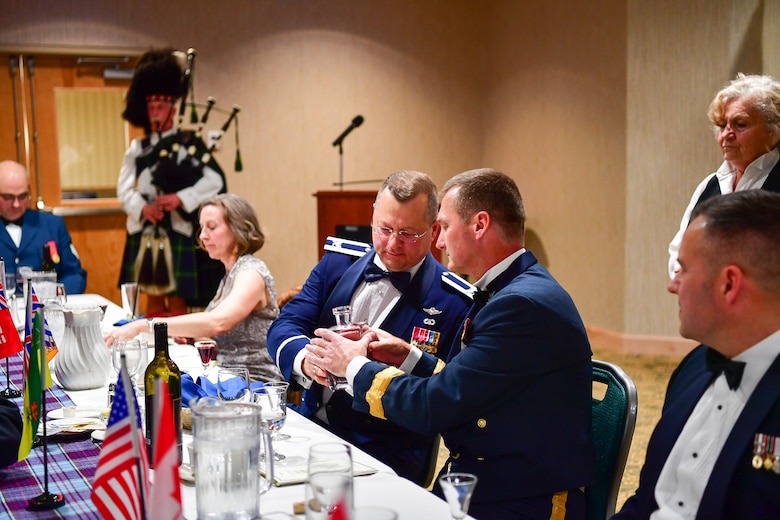 Col. Gregor J. Leist, Western Air Defense Sector commander, passes the port to Canadian Brig. Gen. David Cochrane, 2nd Canadian Air Division commander, during the annual Canadian Mess Dinner marking the 93rd anniversary of the formation of the Royal Canadian Air Force.  The manner in which the port is passed is military service specific.  In case of the Air Force, the port never touches the table to symbolize flight.  The port is used for all of the official toasts during the Mess Dinner.  (U.S. Air Force photo by Kimberly D. Burke)