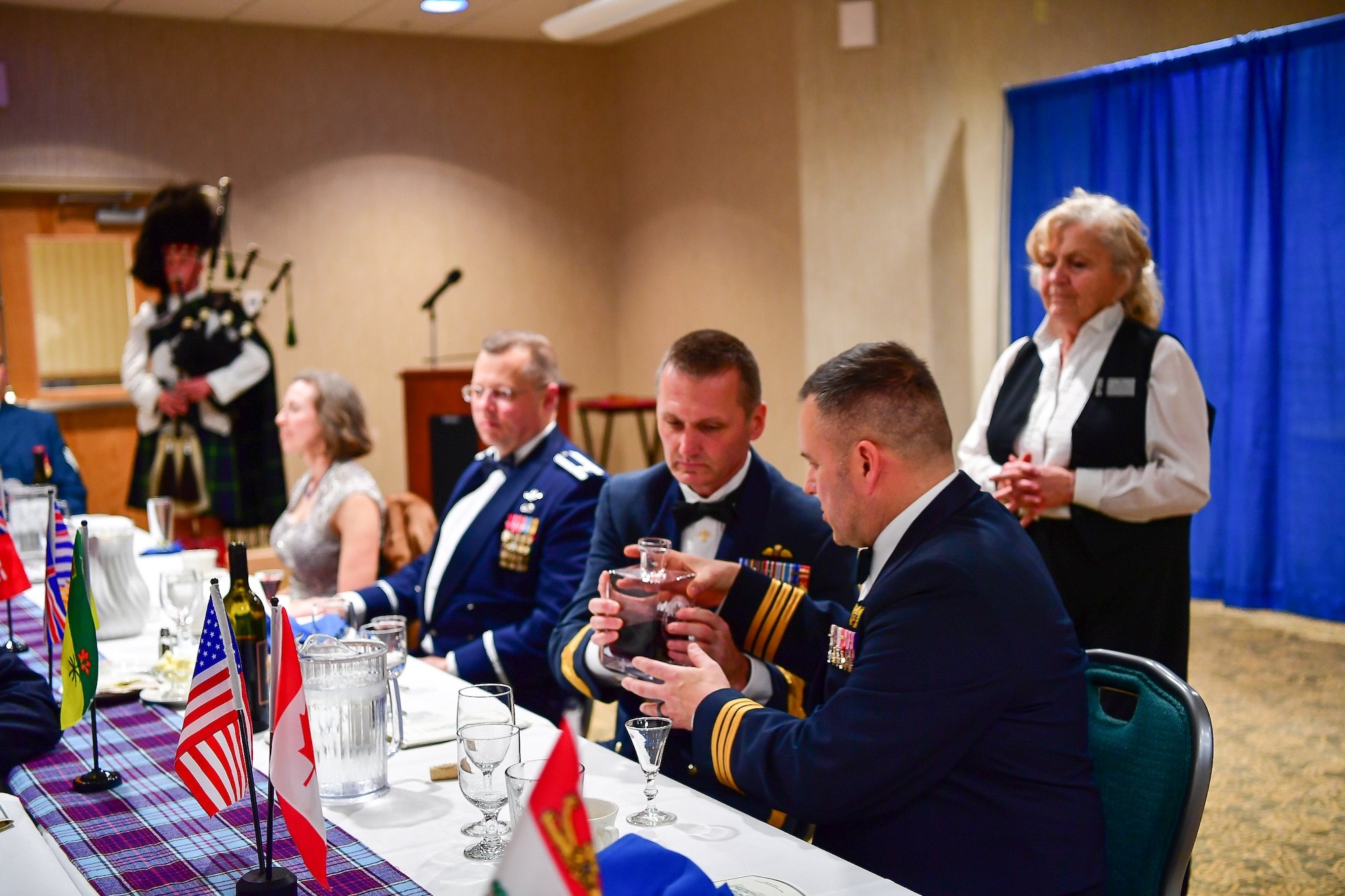Canadian Brig. Gen. David Cochrane, 2nd Canadian Air Division commander, pass the port to Canadian Lt. Col. Matt Wappler, Wester Air Defense Sector Canadian Detachment commander, during the annual Canadian Mess Dinner marking the 93rd anniversary of the formation of the Royal Canadian Air Force.  The manner in which the port is passed is military service specific.  In case of the Air Force, the port never touches the table to symbolize flight.  The port is used for all of the official toasts during the Mess Dinner.  (U.S. Air Force photo by Kimberly D. Burke)