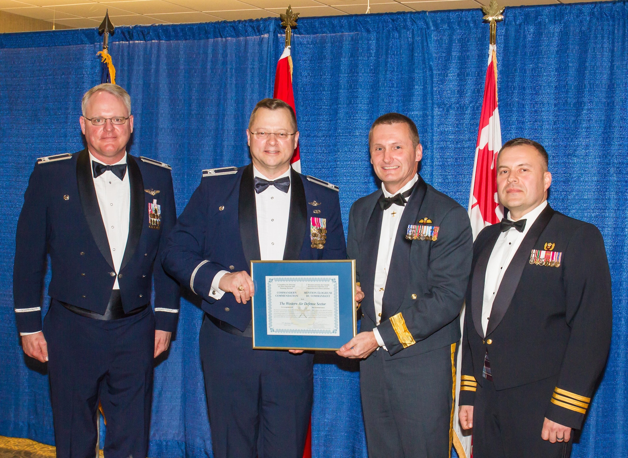 During the annual WADS Canadian Mess Dinner, Canadian Brig. Gen. David Cochrane (middle-right), 2nd Canadian Air Division commander, presents Col. Gregor J. Leist (middle-left), Western Air Defense Sector commander, with the 2nd CAD Commander’s Unit Commendation.  Canadian Lt. Col. Matt Wappler (right), WADS Canadian Detachment commander, nominated WADS for consistently providing critical live and virtual training to Canadian aerospace controllers from the 51 Aerospace Control and Warning (Operational Training) Squadron located at North Bay, Ontario. (Courtesy photo by Conrad Neumann III)