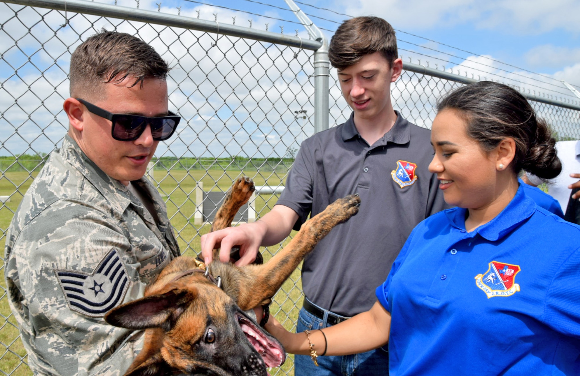 John Jay High School Air Force Junior Reserve Officer Training Corp cadets Jackson Getz and Shadicy Garza pet Delarge, a puppy from the Military Working Dog program held by Tech. Sgt. Nicholas Lewis, an 802nd Security Force Squadron military working dog handler , April 19, 2017 at Joint Base San Antonio-Lackland, Texas. The students toured engine and structural engineering shops at the 433rd Airlift Wing. (U.S. Air Force photo by Tech. Sgt. Carlos J. Trevino) (released)