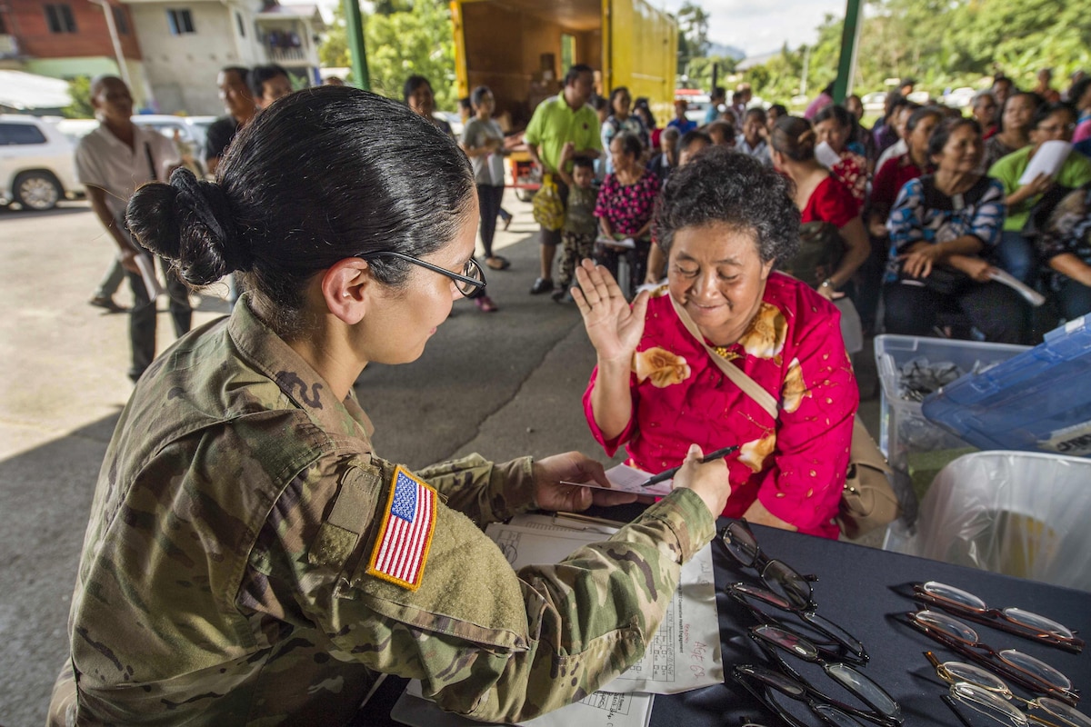 A soldier examines a patient's eyes.