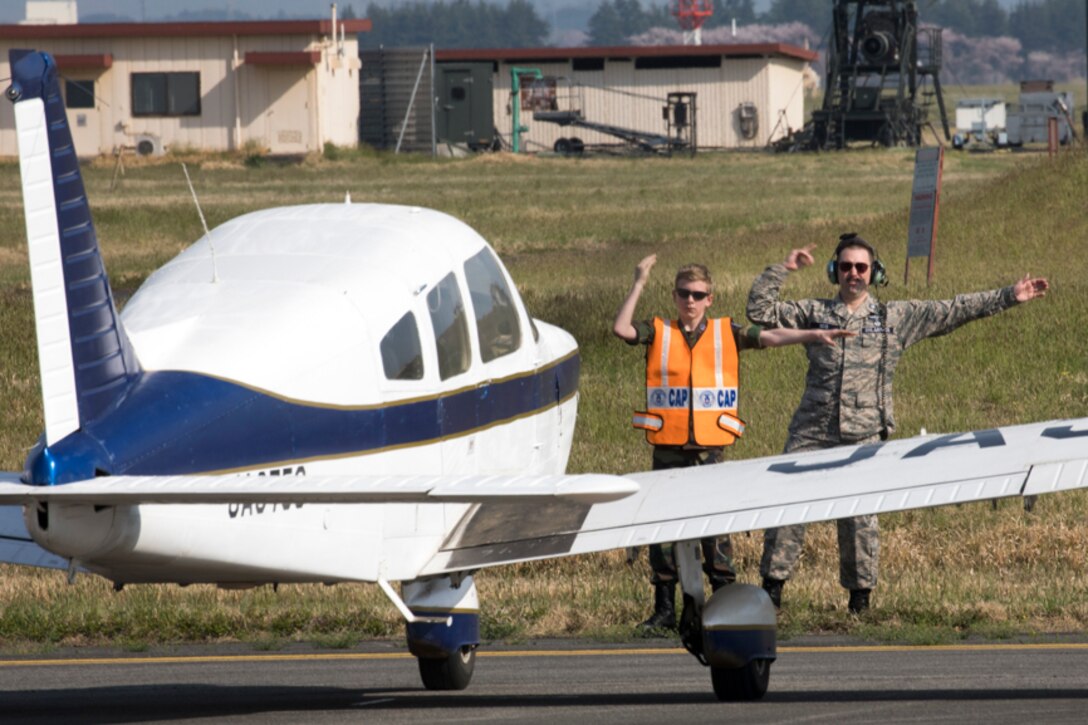 Lt. Col. Adam Boyd, Civil Air Patrol National HQ-103 commander, and Cadet Master Sgt. Simon Amport, CAP cadet, marshal in a civilian aircraft landing at Yokota Air Base, Japan, during the Kanto Plain Mid-Air Collision Avoidance Conference, April 15, 2017. The conference brought together military and civilian pilots from all over Japan to focus on flight safety and base flight procedures. (U.S. Air Force photo by Yasuo Osakabe)