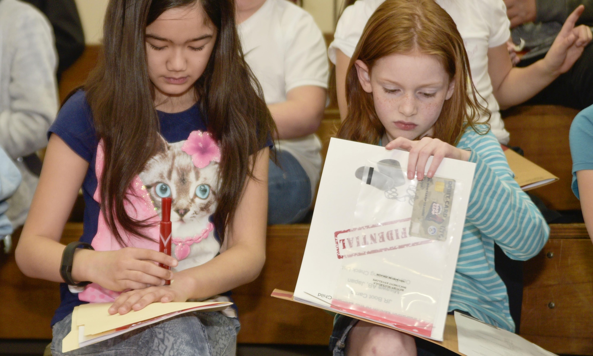 Two girls review their official personnel folder prior to the start of the Spring Break Junior Boot Camp event at Misawa Air Base, Japan, April 7, 2017. During the event there was an in processing line, obstacle course and drill practice followed by closing ceremony and dinner. (U.S. Air Force photo by Staff Sgt. Melanie A. Hutto)