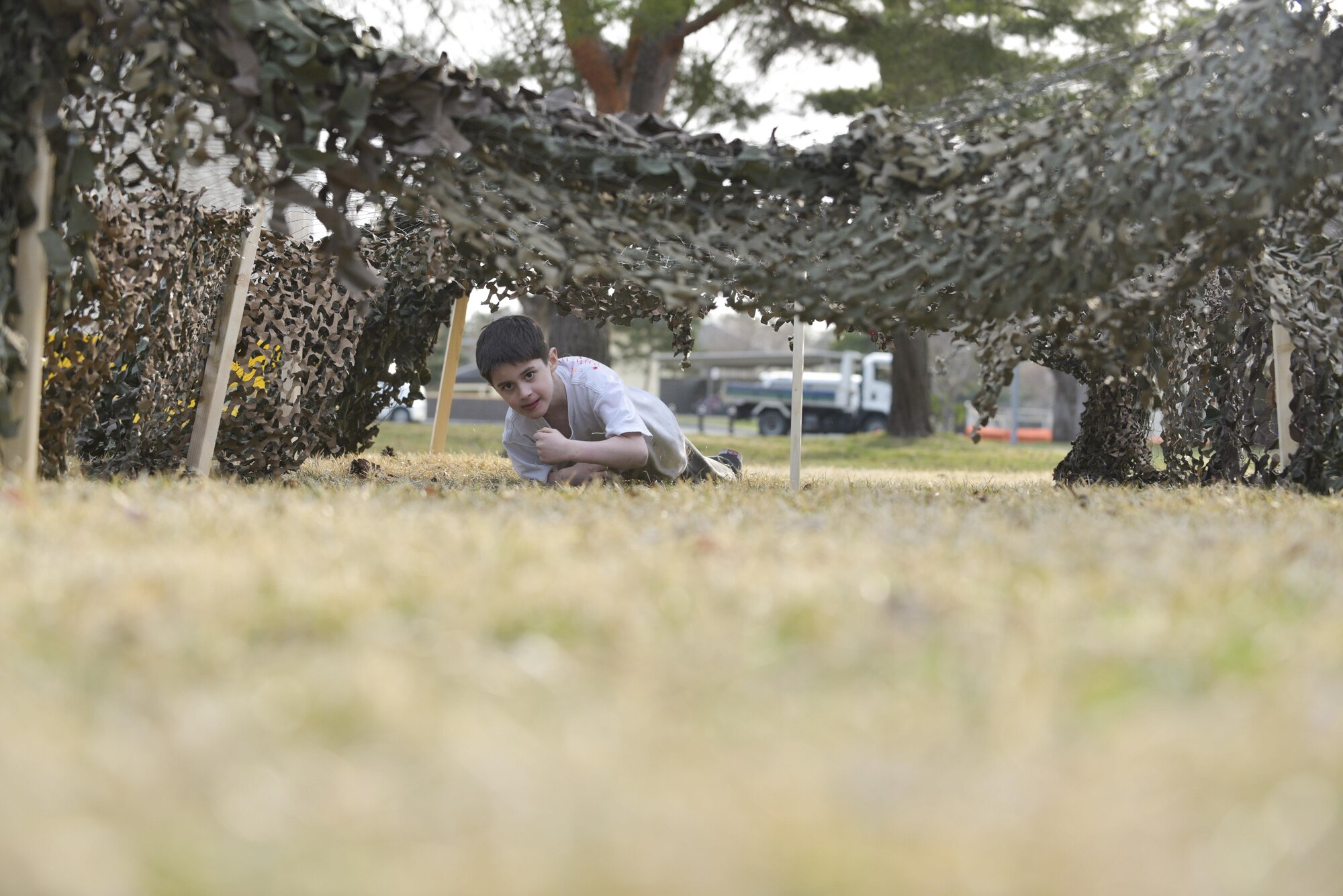 A young boy low crawls under a net as part of the obstacle portion of the Spring Break Junior Boot Camp event at Misawa Air Base, Japan, April 7, 2017. Immediately following the obstacle course they marched straight into learning basic facing movements from the Robert D. Edgren High School Junior Reserve Officer Training cadets. (U.S. Air Force photo by Staff Sgt. Melanie A. Hutto)
